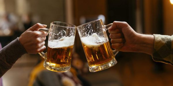 Close-up of two people toasting with beer.